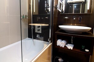A modern bathroom with a glass-enclosed shower, a standalone bathtub, and a vanity with a large sink and towel storage.