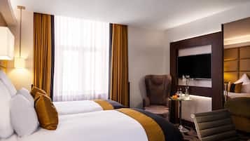 Une chambre d’hôtel avec deux lits, une chaise, une petite table avec un vase et un téléviseur.