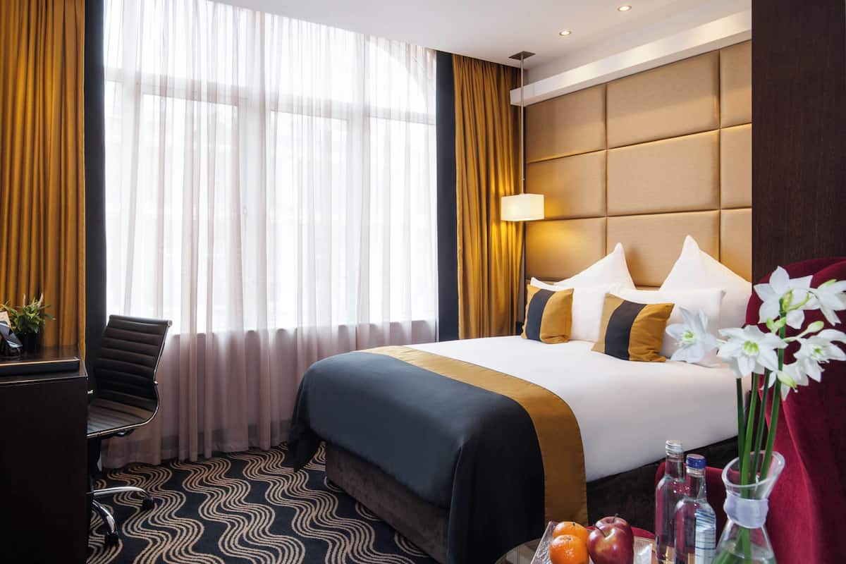 A hotel room with a large bed, a desk, and a chair.