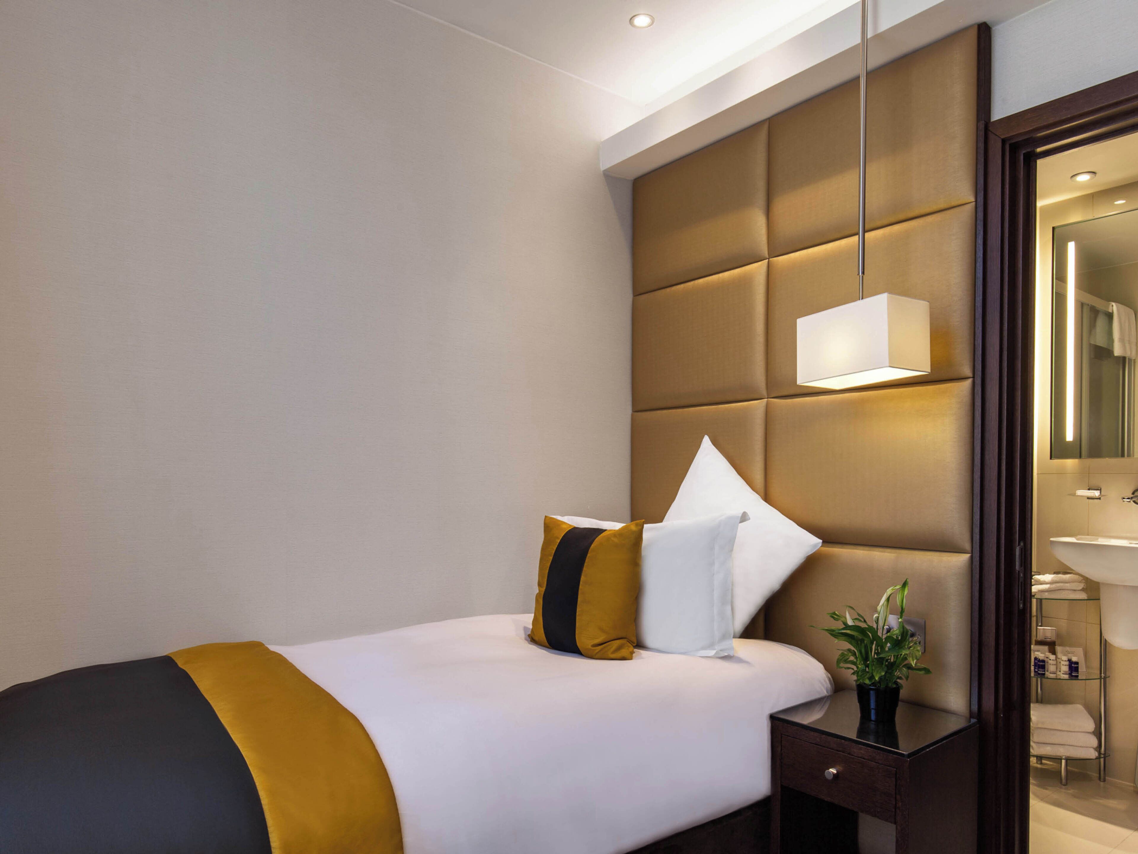 Una habitación de hotel con cama, mesita de noche y espejo.