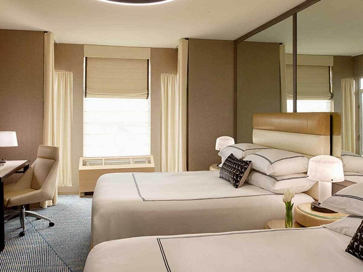 A hotel room with two beds, a desk, and a chair.