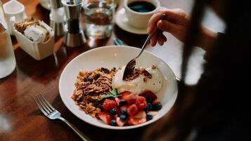 A breakfast setting with a bowl of yogurt, granola, strawberries, and blueberries.