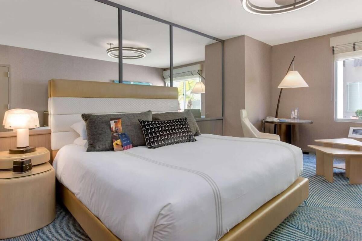 A hotel room with a large bed, bedside tables, a desk, and a chair.