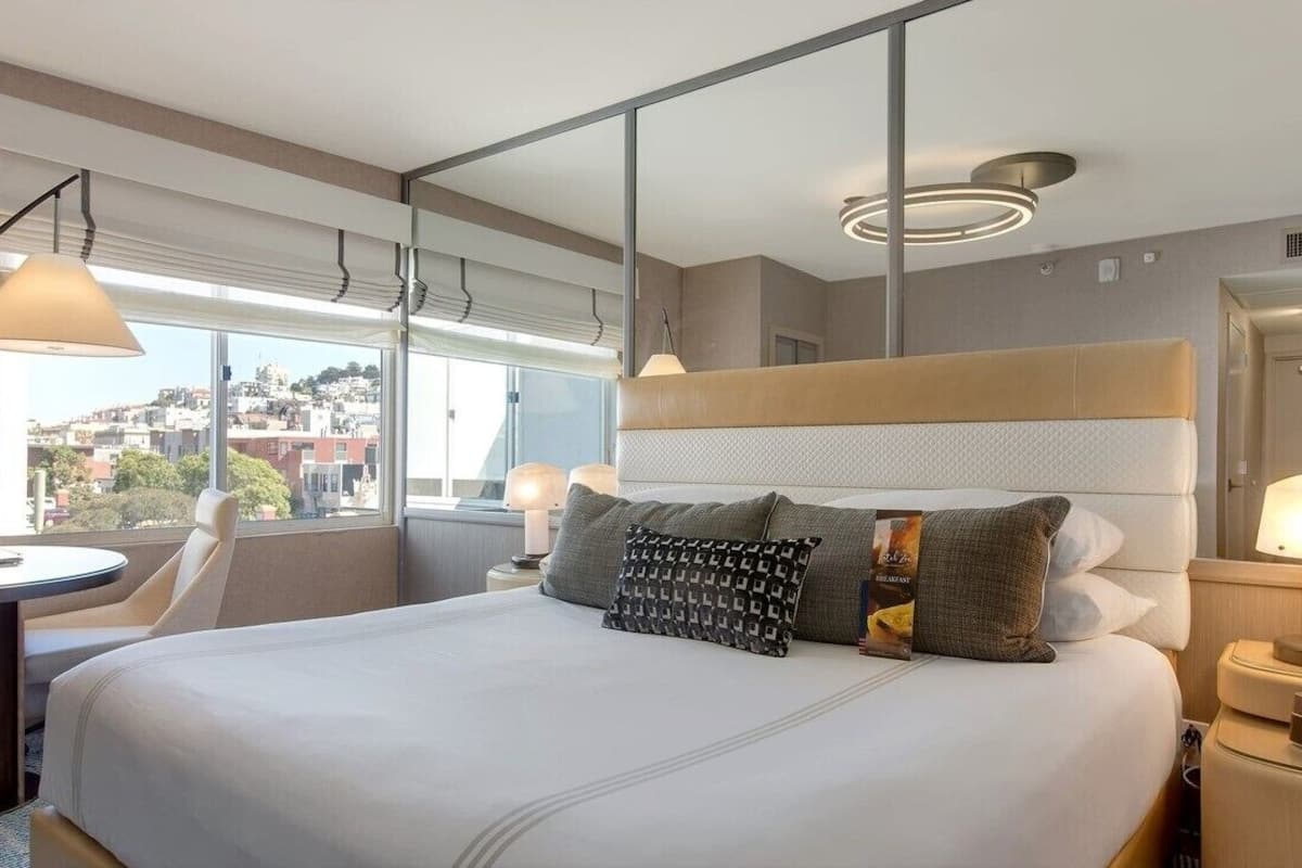 Une chambre d’hôtel moderne avec un grand lit, un bureau et une vue sur la ville.