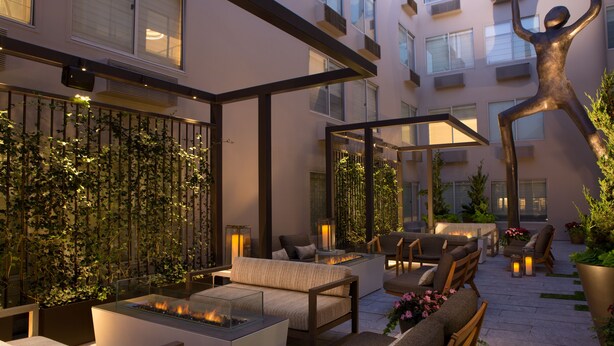 An outdoor patio area with modern furniture, a fire feature, and a decorative metal sculpture.