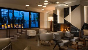 A modern lobby with a fireplace, comfortable seating, and a staircase leading to upper floors.