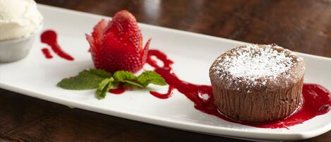 A dessert plate with a chocolate cake, a strawberry, and a scoop of ice cream.