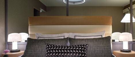 Habitación de hotel con una cama grande, dos lámparas de noche, una lámpara de techo moderna y una mesita de noche con un jarrón y una lámpara.