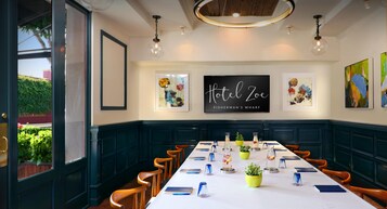 Un salón de conferencias con una mesa larga, sillas y un cartel que dice 'Hotel Zoe Fisherman's Wharf'.