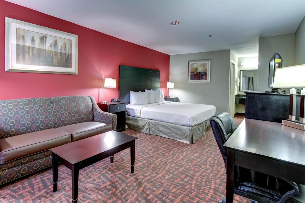 Une chambre d’hôtel avec un lit, un canapé, un bureau et une chaise.