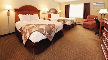 A hotel room with two beds, a desk, a chair, and a desk lamp.