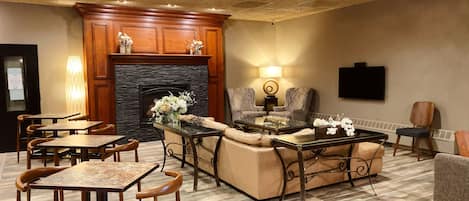 A spacious living area with a fireplace, comfortable seating, and a television mounted on the wall.