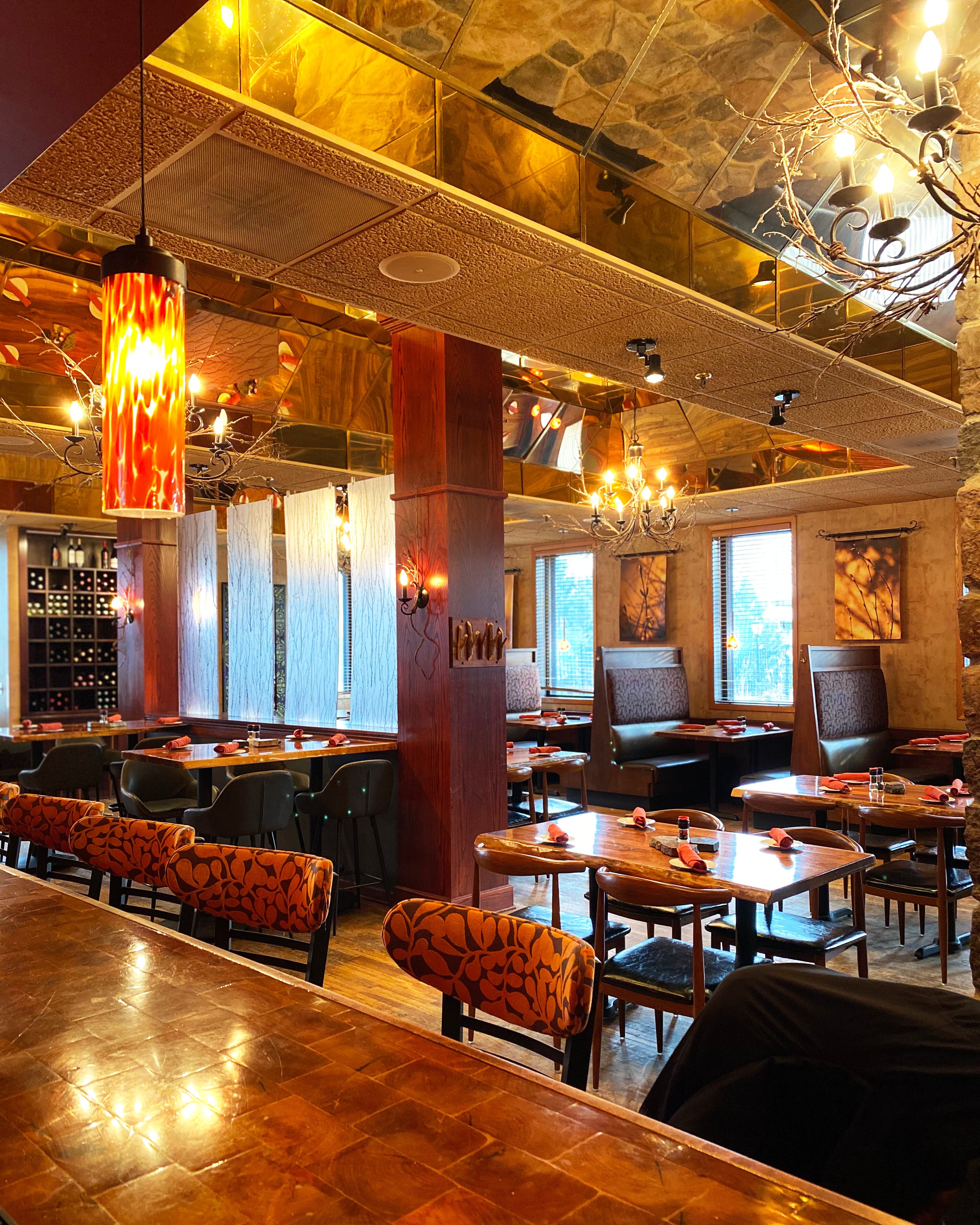 A restaurant interior with wooden tables, cushioned booths, and a warm, ambient lighting.