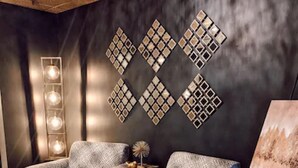 Una sala de estar moderna con una pared oscura, un accesorio de iluminación decorativo y una obra de arte con motivos.