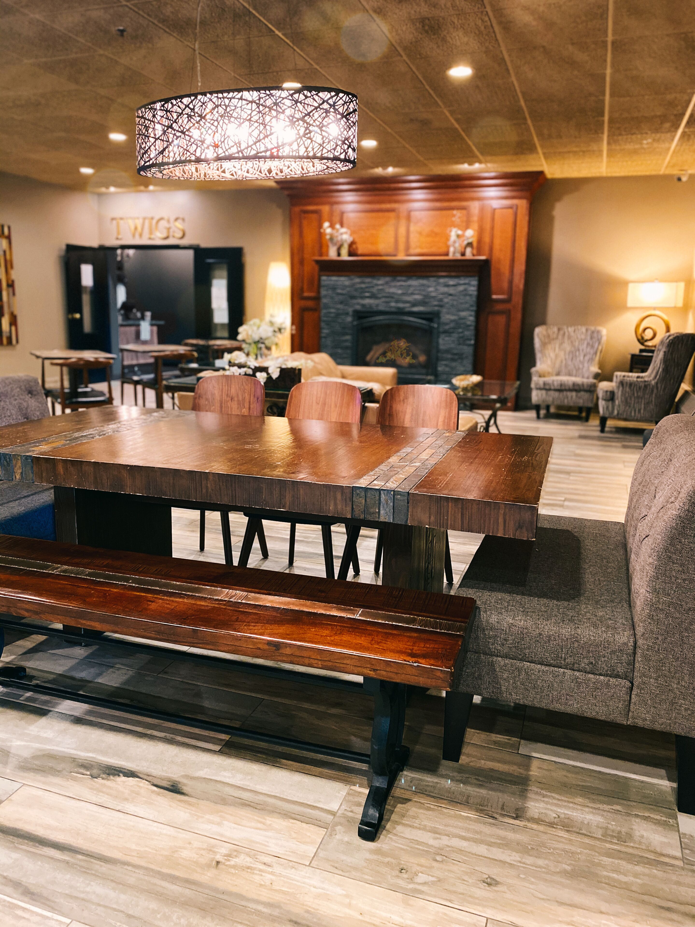 A dining area with a wooden table and benches, a fireplace, and a chandelier.