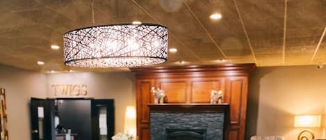 A dining area with a wooden table and benches, a fireplace, and a chandelier.