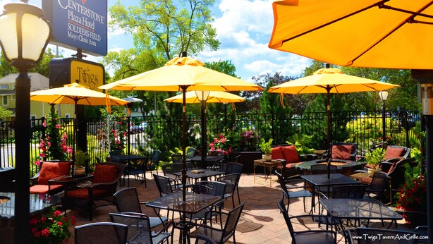 Un patio al aire libre con sombrillas amarillas, muebles de mimbre y un letrero del Hotel Centerstone Plaza.