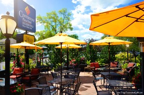 An outdoor patio area with yellow umbrellas, wicker furniture, and a sign for Centerstone Plaza Hotel. - Centerstone Plaza Hotel Soldiers Field - Mayo Clinic Area (Rochester)