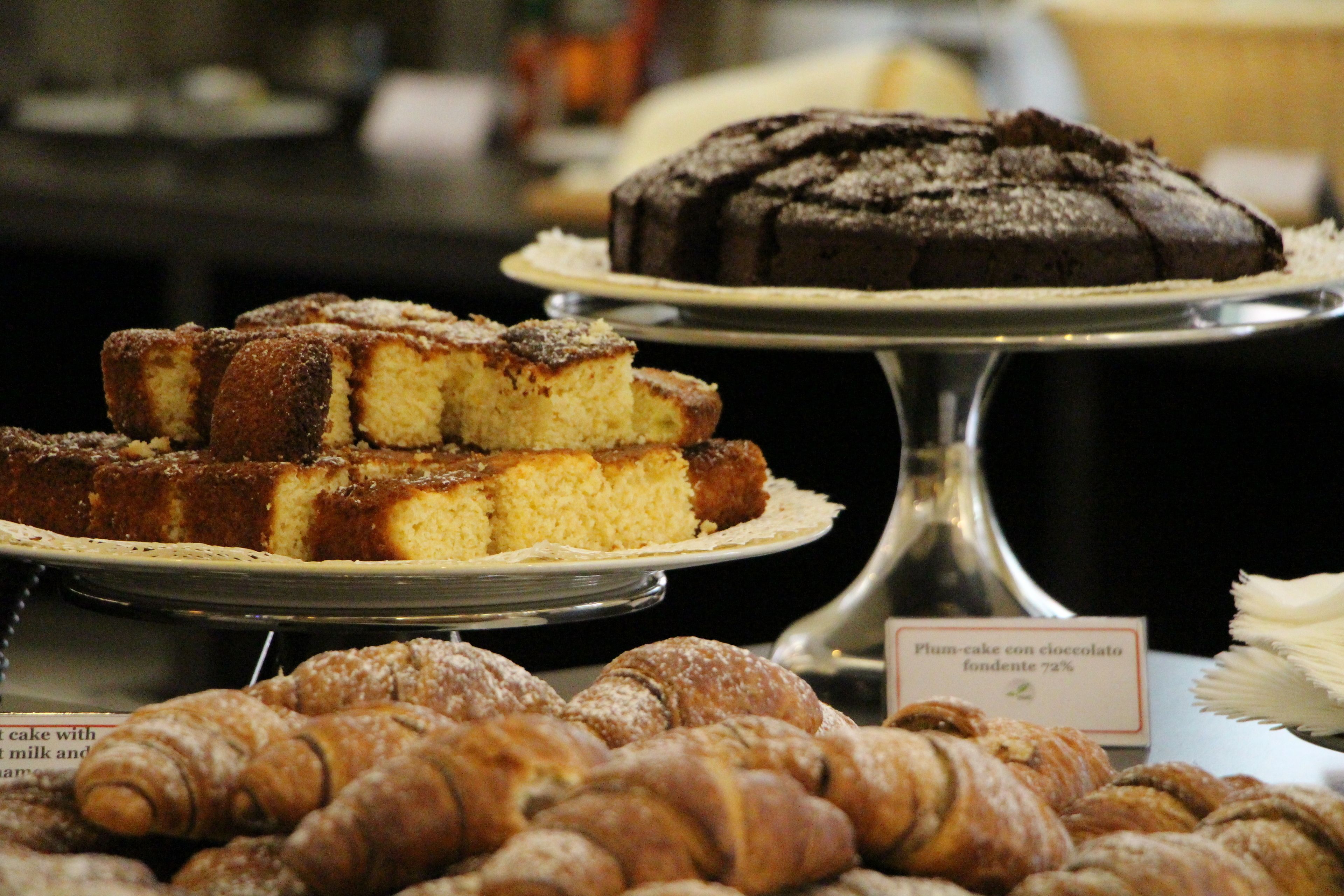 Una exhibición de productos horneados, incluyendo un pastel de chocolate, una porción de pastel y varias piezas de pastelería.