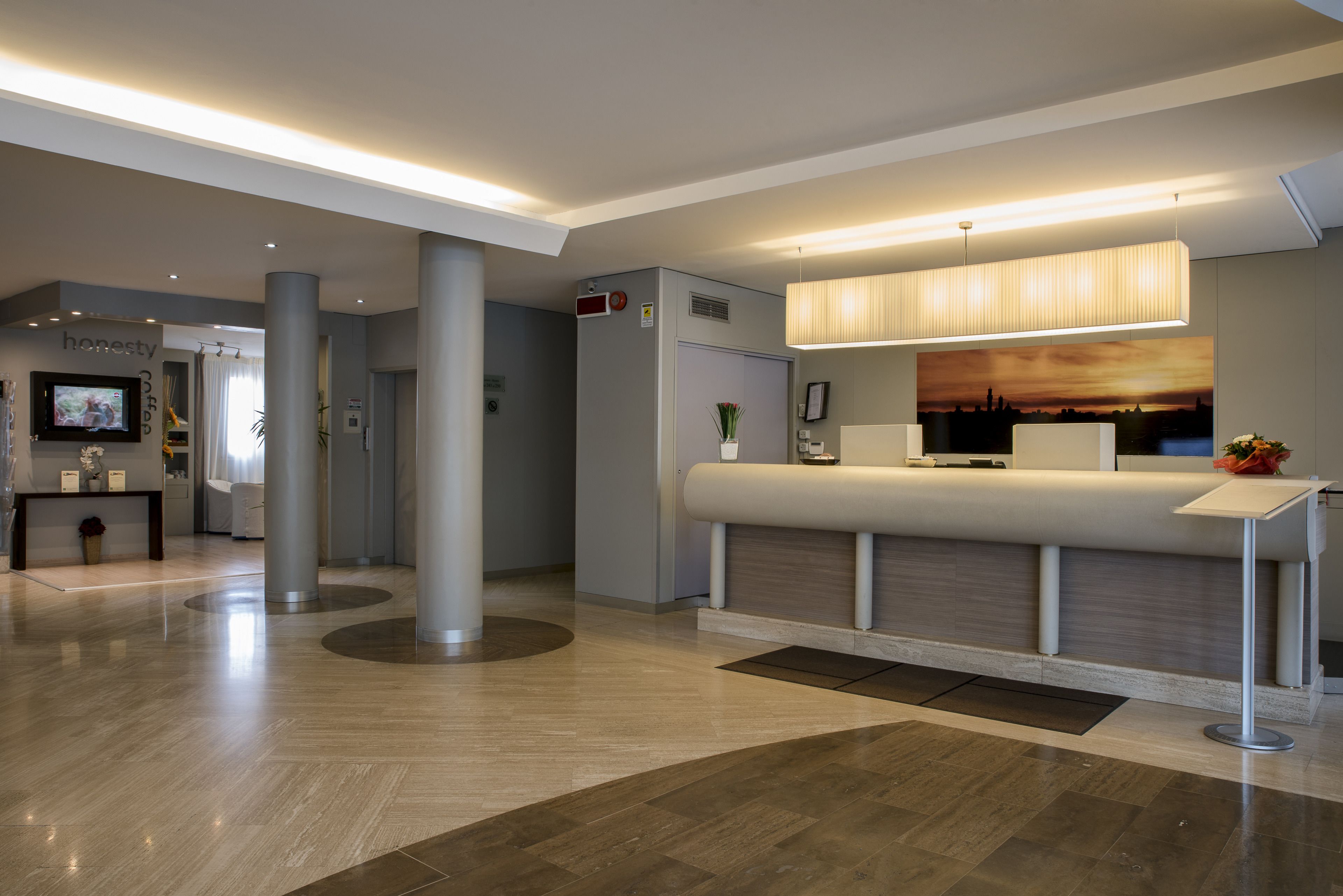 A modern reception area with a reception desk, a large wall-mounted TV, and a seating area with a view of the sunset.
