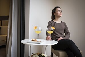 A person seated at a small round table with a plate of food and two glasses of orange juice.