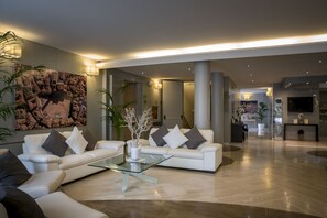 Relax in our spacious lobby with a comfortable seating area, featuring a sofa and armchairs, and a beautiful abstract artwork.