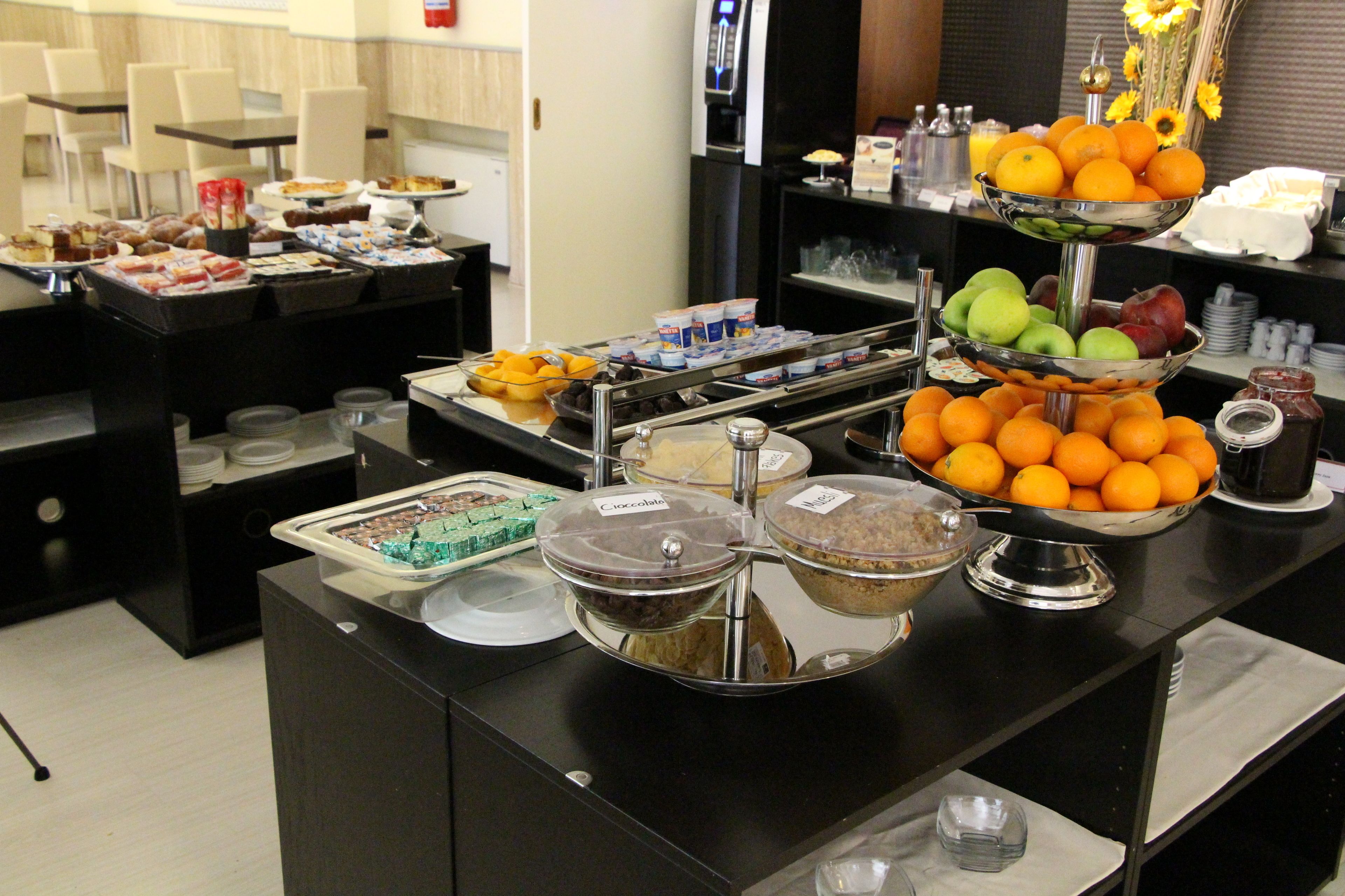 Un buffet proposant une variété de plats, notamment des fruits, des pâtisseries et des boissons.