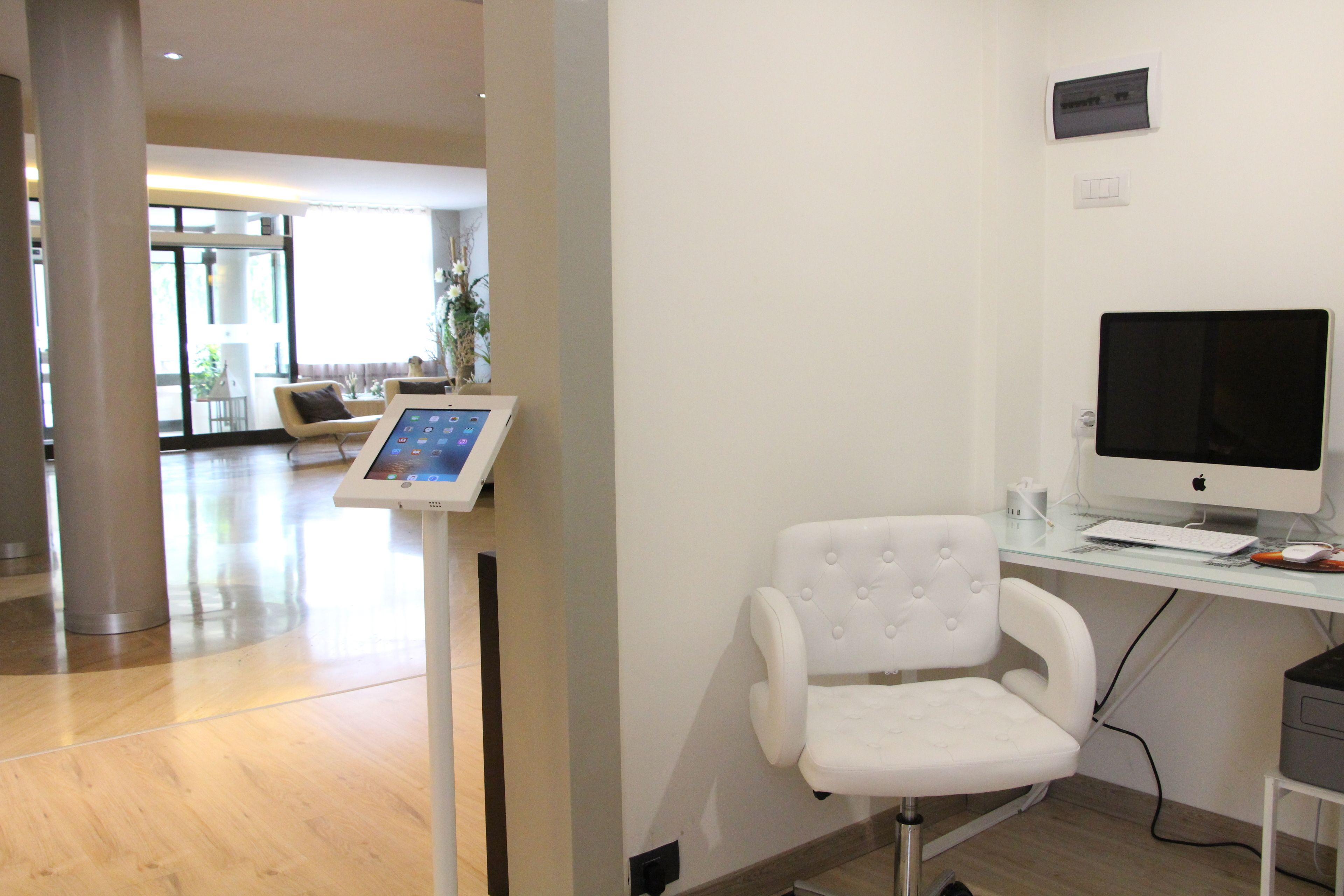 A modern office with a white chair, a desk with a computer, and a control panel.