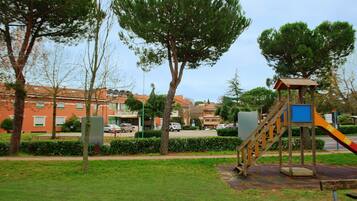 A playground with a slide and stairs, surrounded by trees and buildings.