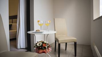 A small, modern room with a round table, two chairs, a bouquet of flowers, and two glasses of a yellow beverage.