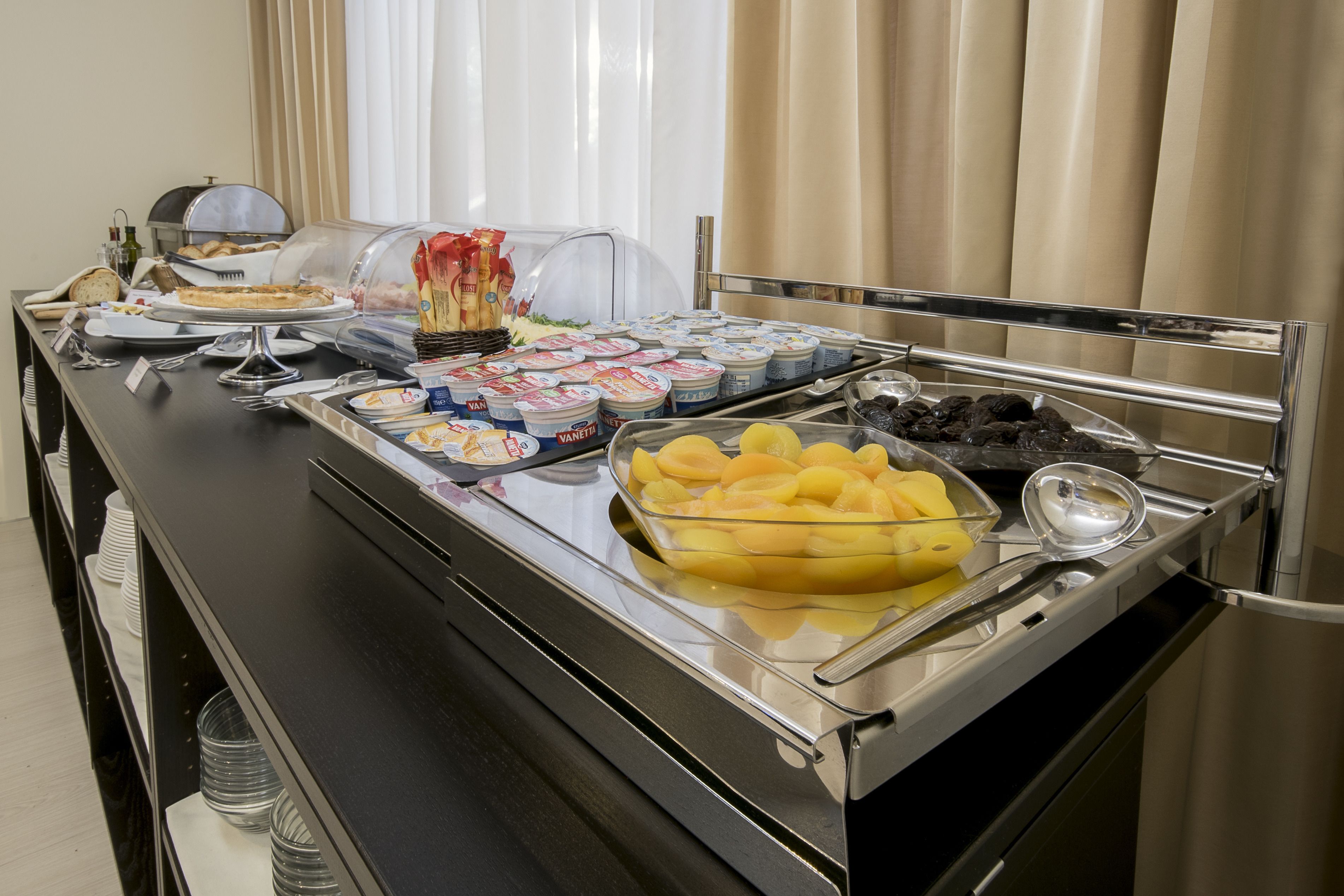 Ein reichhaltiges Buffet mit verschiedenen Speisen, darunter Obst, Joghurts und Gebäck.