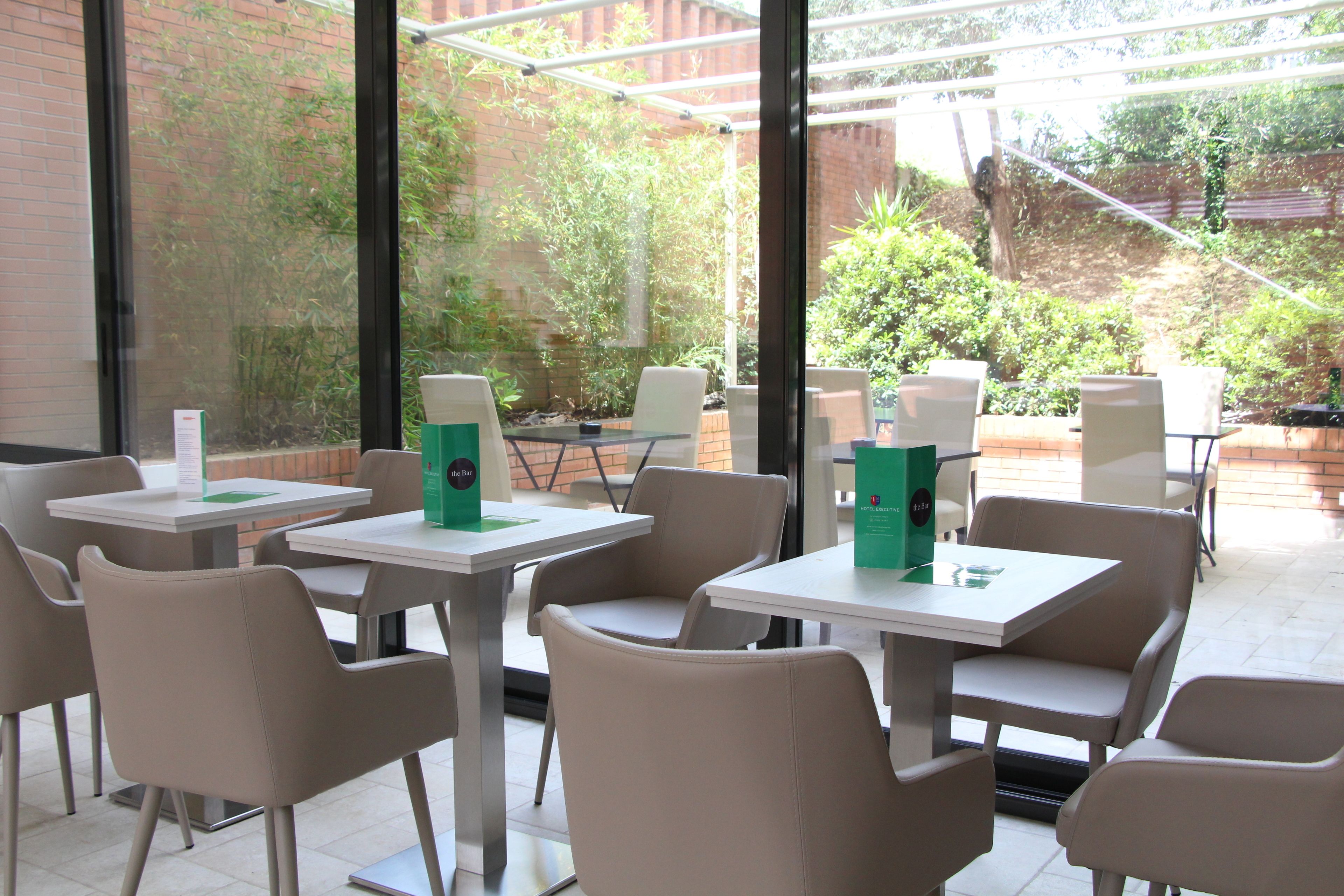 Café con terraza, mesas y sillas, y vistas al exterior.