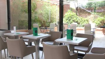 Café con terraza, mesas y sillas, y vistas al exterior.