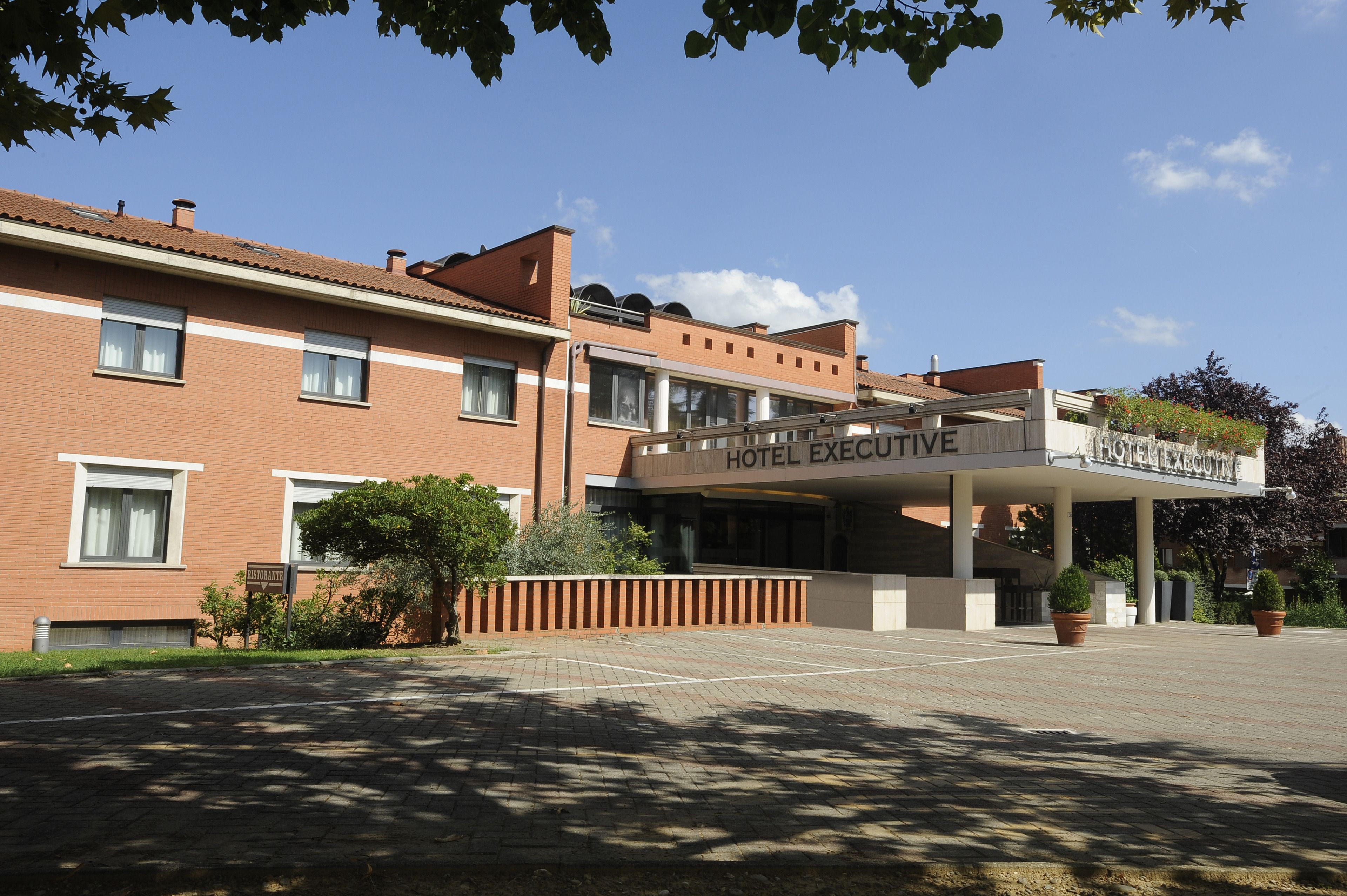 Un hotel con facciata in mattoni, un ingresso coperto e un cartello con la scritta 'HOTEL EXECUTIVE'.