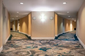 A hotel hallway with carpeted floors, recessed lighting, and a central light fixture. - Hilton San Diego Airport/Harbor Island (San Diego)