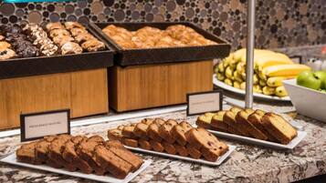 A buffet with various baked goods, including muffins and bread, displayed on a marble countertop.