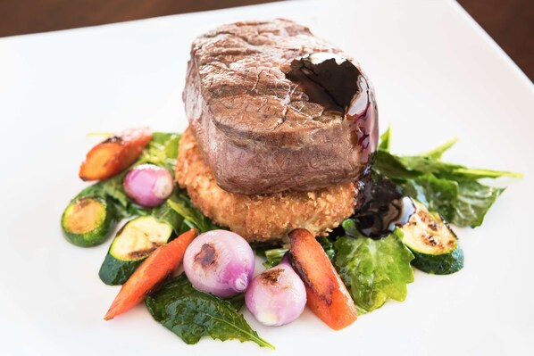 Un plato con un filete de res, verduras y una ensalada.