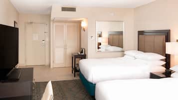 A hotel room with two beds, a desk, a TV, and a mirror.
