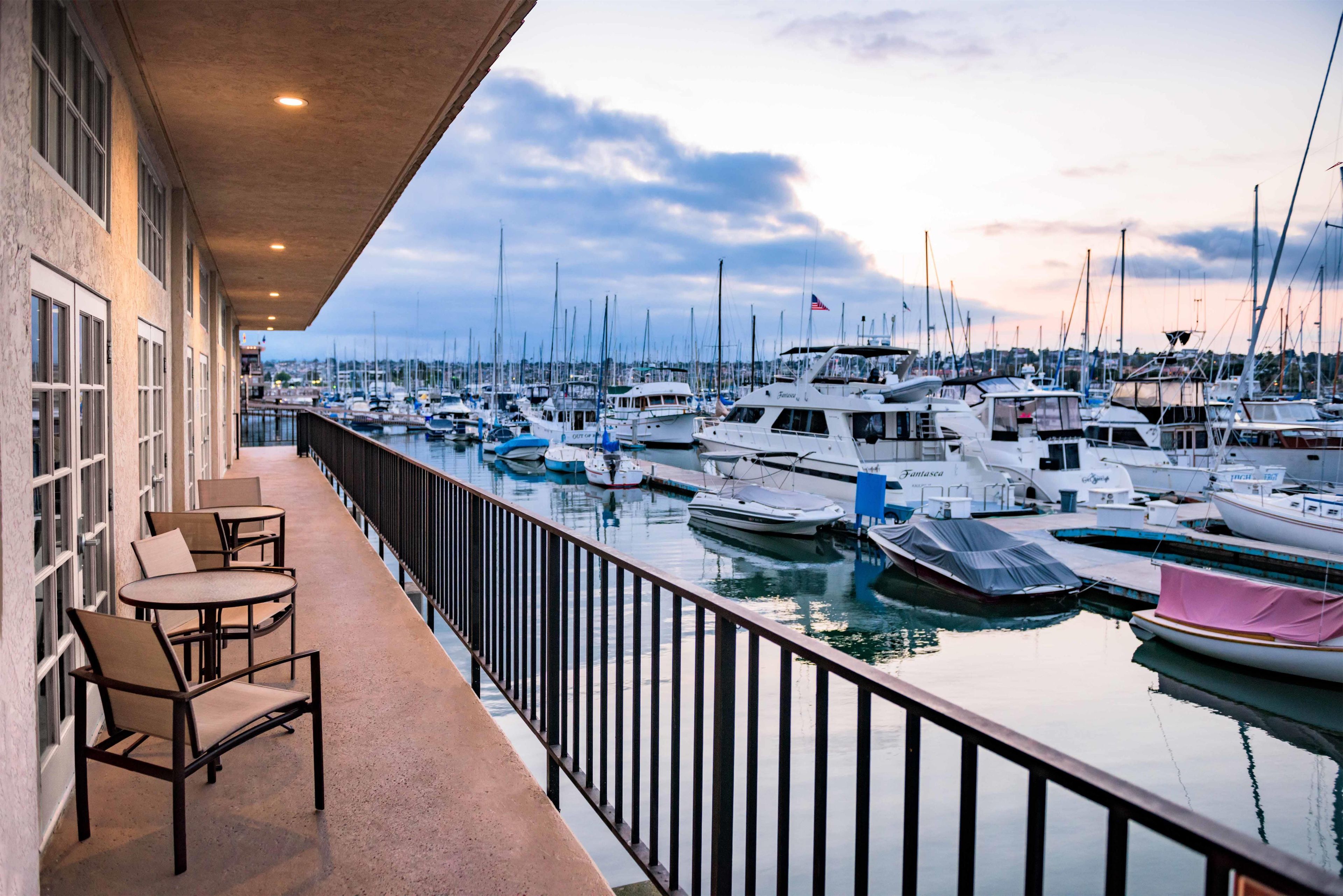 Un port de plaisance avec des bateaux amarrés, un balcon avec des chaises et une vue sur l’eau.