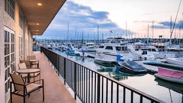 Marina com barcos atracados, varanda com cadeiras e vista para a água.
