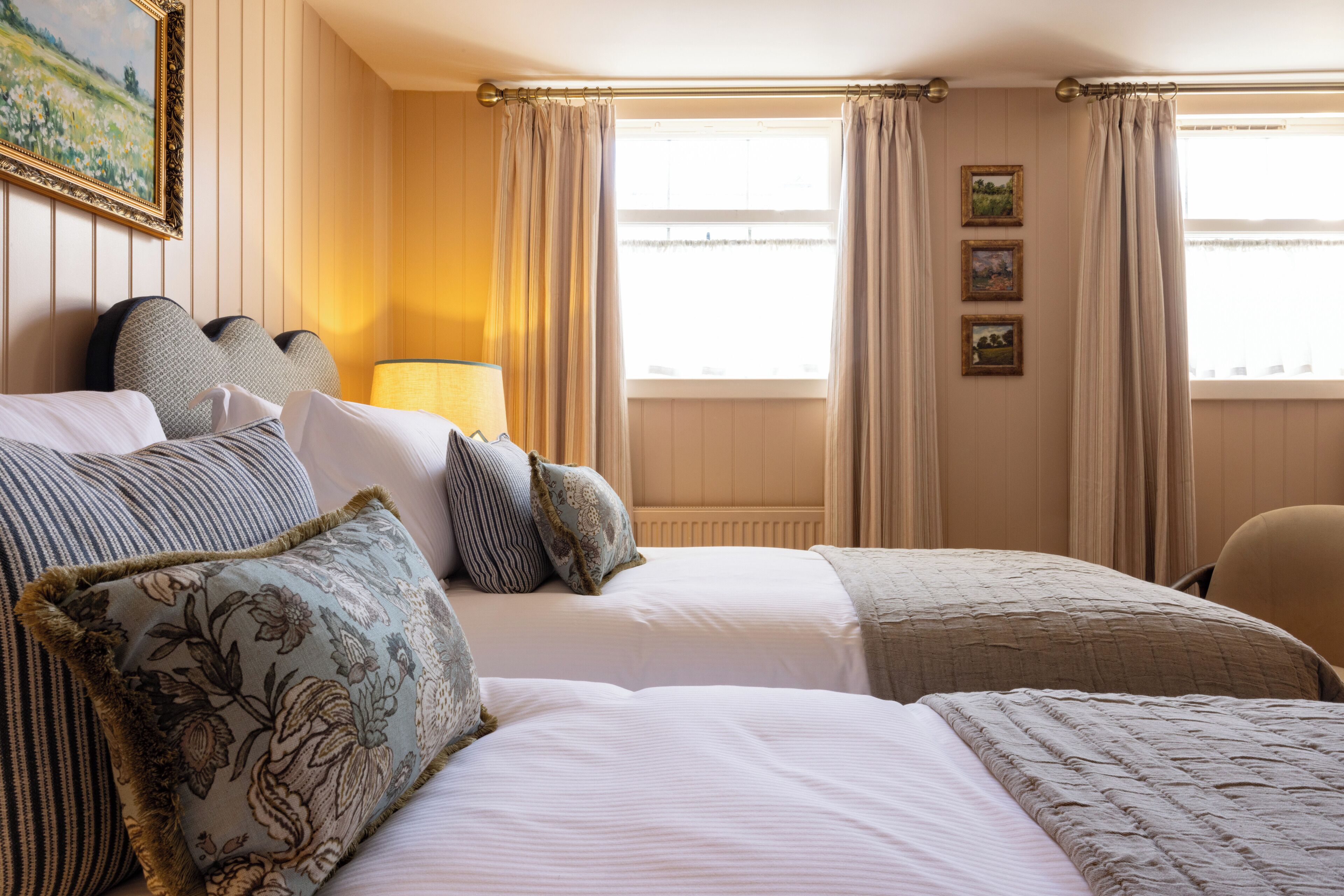 A hotel room with two beds, a lamp, and a window with curtains.