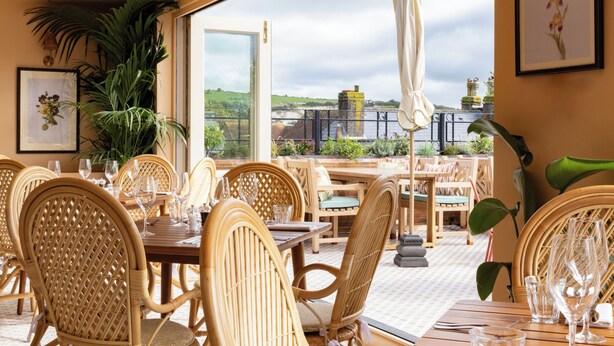 A restaurant with wicker furniture, outdoor seating, and a view of the countryside. - The White Hart - A Heartwood Inn (Lewes)