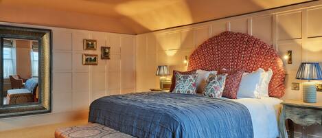 A bedroom with a large bed, a mirror, and a decorative headboard.