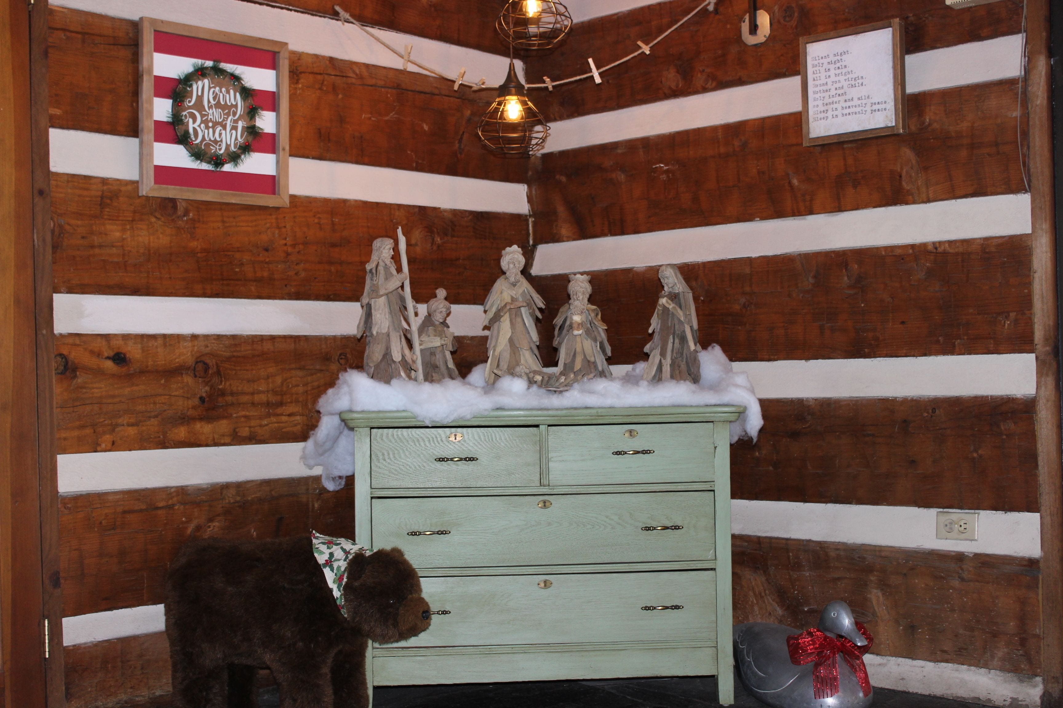 Een rustieke houten kamer met een groene dressoir, een kerstkrans en een klein engelbeeldje.