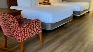 A hotel room with two beds, a wooden chair, a table, and a lamp. - Great Smokies Inn Cherokee (Cherokee)