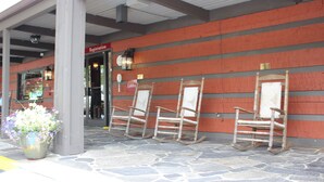 A building entrance with a registration sign, a lobby sign, and three rocking chairs lined up against a wall. - Great Smokies Inn Cherokee (Cherokee)