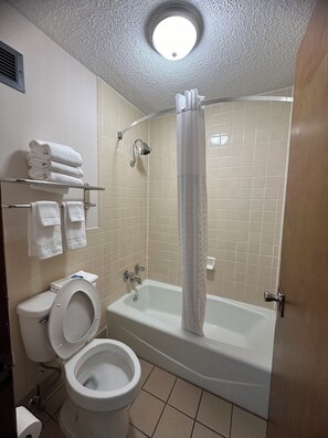 A bathroom with a toilet, sink, and bathtub with a shower curtain.