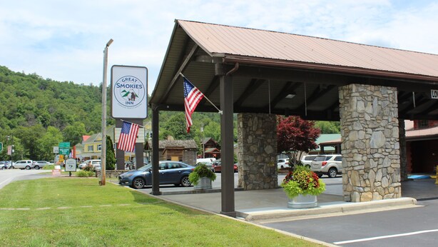 A hotel with a covered outdoor area, stone pillars, and American flags.