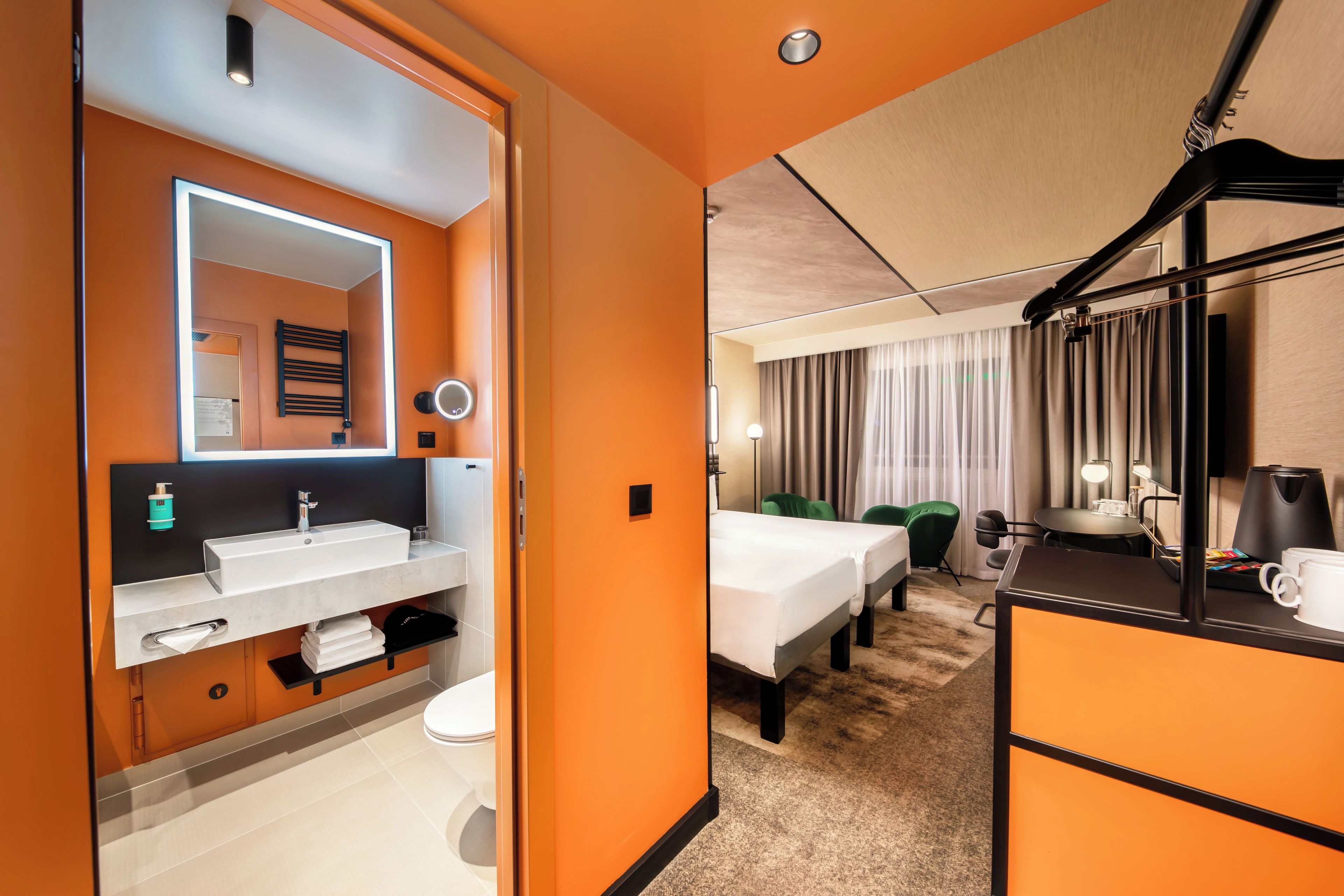 Habitación de hotel con baño, cama, escritorio y cafetera.