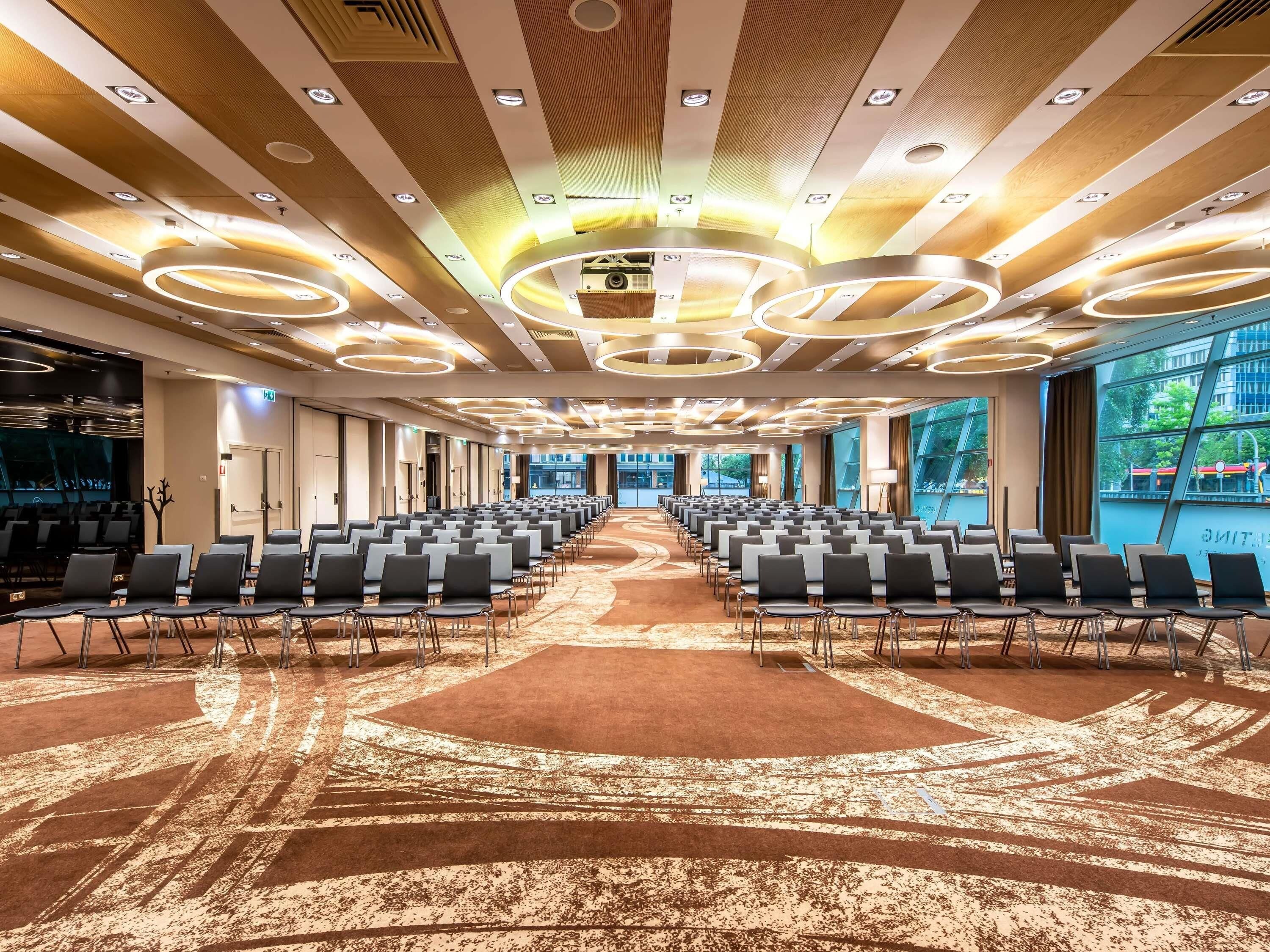 A conference room with rows of chairs, a patterned carpet, and a modern ceiling design.